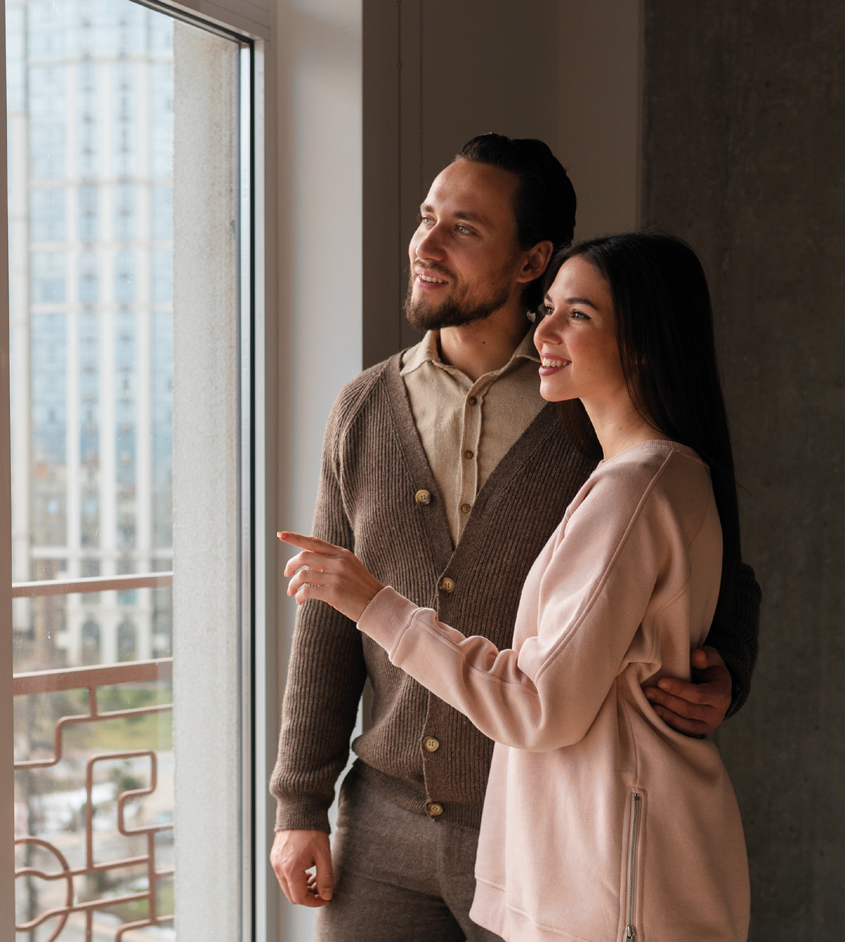 Een stel kijkt samen uit het raam van hun nieuwe woning